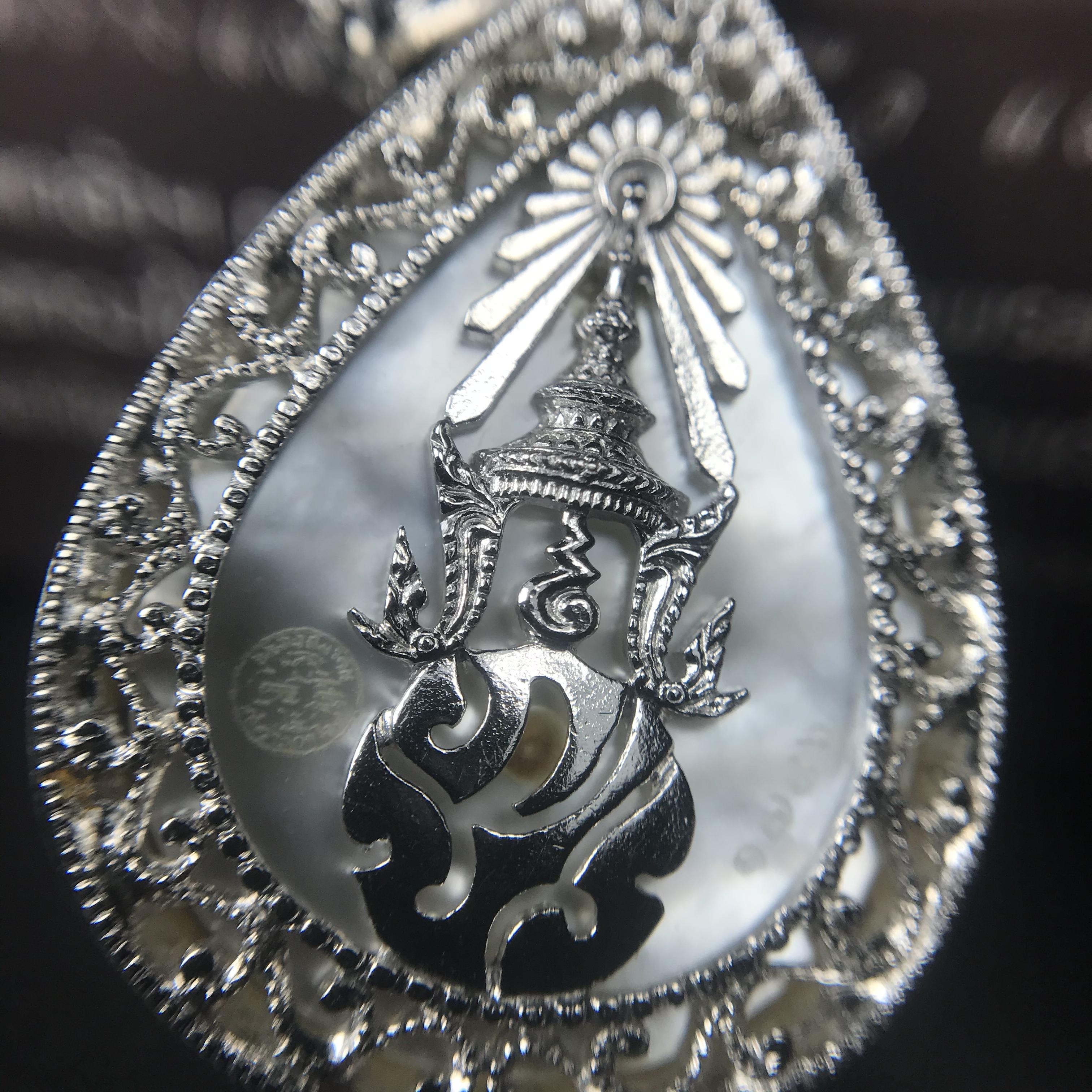 พระพุทธชินราช ภปร. โครงการ "เพราะแผ่นดินนี้ คือ แผ่นดินเกิด" ปี2548(รุ่นแรก) เหรียญทรงหยดน้ำ ขนาด 21 x 31 มม. เนื้อเงินสามกษัตริย์ องค์พระชุบสามกษัตริย์ ล้อมด้วยกรอบเงินชุบทองคำขาวสลักเสลาเป็นลวดลายละเอียดอ่อน ส่วนพื้นองค์พระเป็นเปลือกหอยมุข