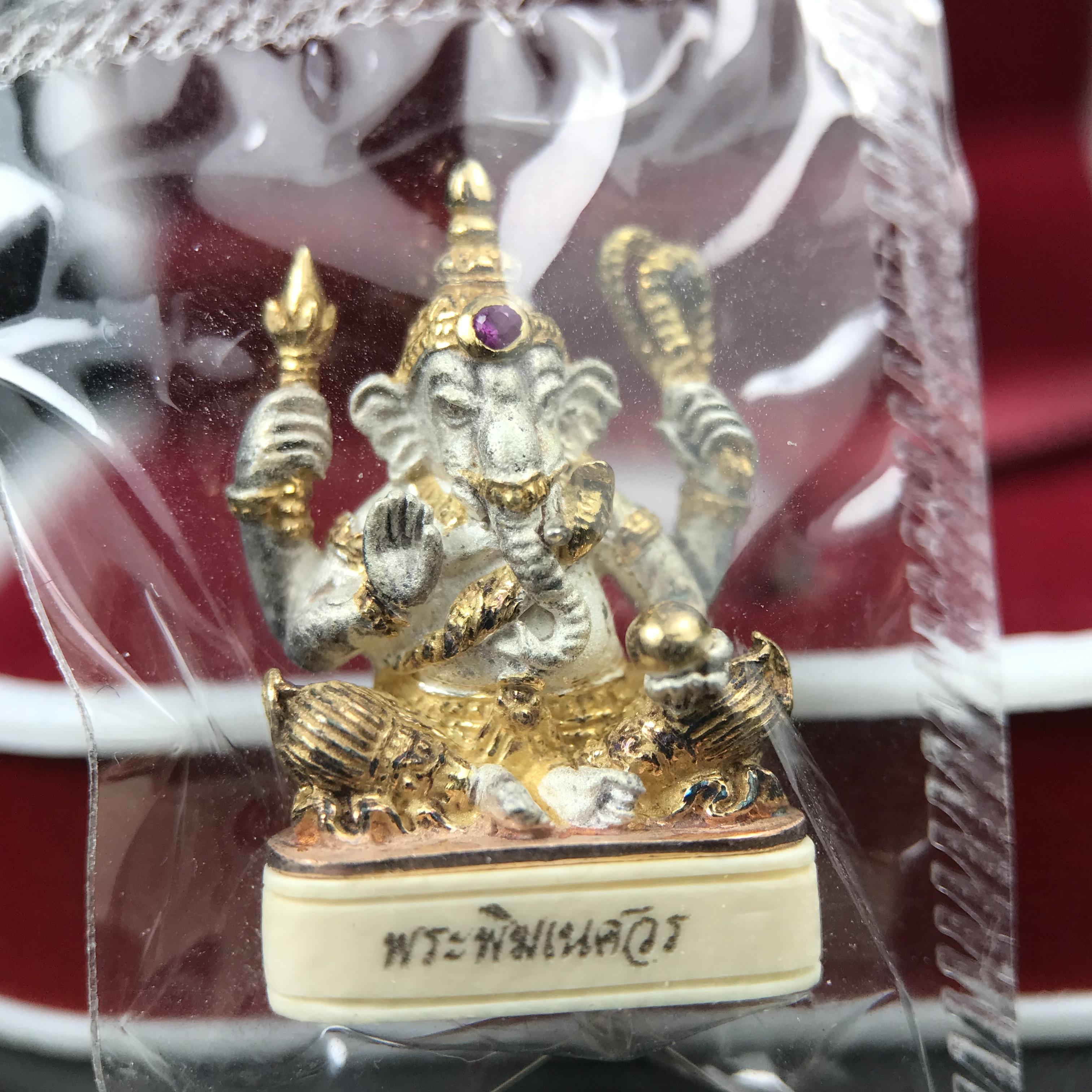 พระพิฆเนศวร รุ่น คชสารหมื่นปี รูปเหมือนพระพิฆเนศวรนั่งประทานพรฐานงาช้างแมมมอสขนาดห้อยคอ เนื้อเงินชุบสามกษัตริย์ขัดเงา พิมพ์เล็ก สูง 2.2 ซม. ฝังพลอยทับทิมแท้ พิธีมหาเทวาภิเษก ณ. เทวสถานโบสถ์พราหมณ์ (เสาชิงช้า) โดยเกจิคณาจารย์ทั่วประทศ ปี 2545(หมายเลข ๓๐)