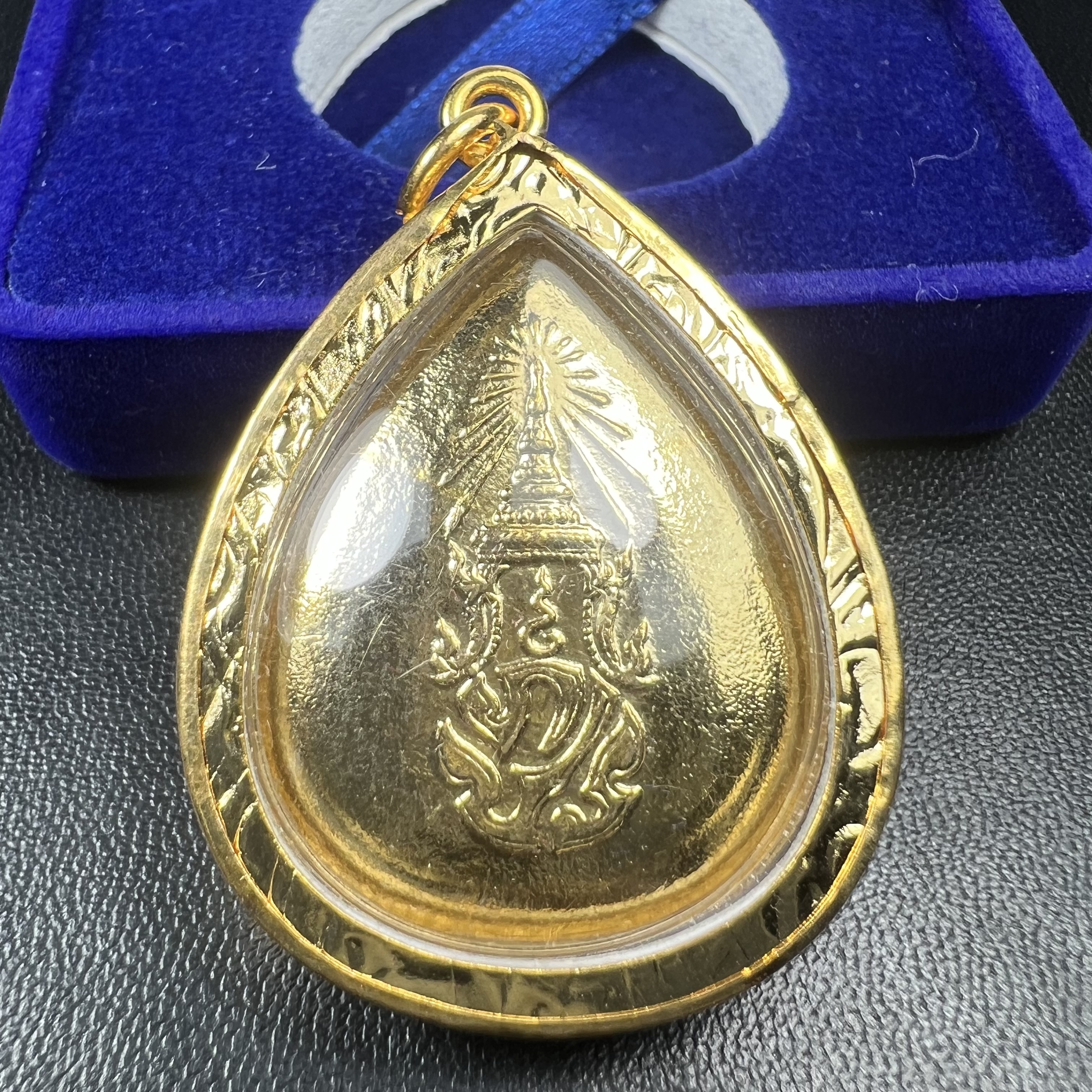 เหรียญพระพุทธสิงหธรรมมงคล ภปร. ปี 2547 ทรงหยดน้ำ ด้านหลังมี ภ.ป.ร. (ชนวนเก่า)เนื้อโลหะผสม ชุบทองเงา สูง 3.3ซม.พิธีใหญ่ มวลสารดี ปลุกเสกวัดพระแก้ว(งานเลี่ยมกรอบเดิมจากผู้จัดสร้างห่อหุ้มด้วยทองนพเกล้า)