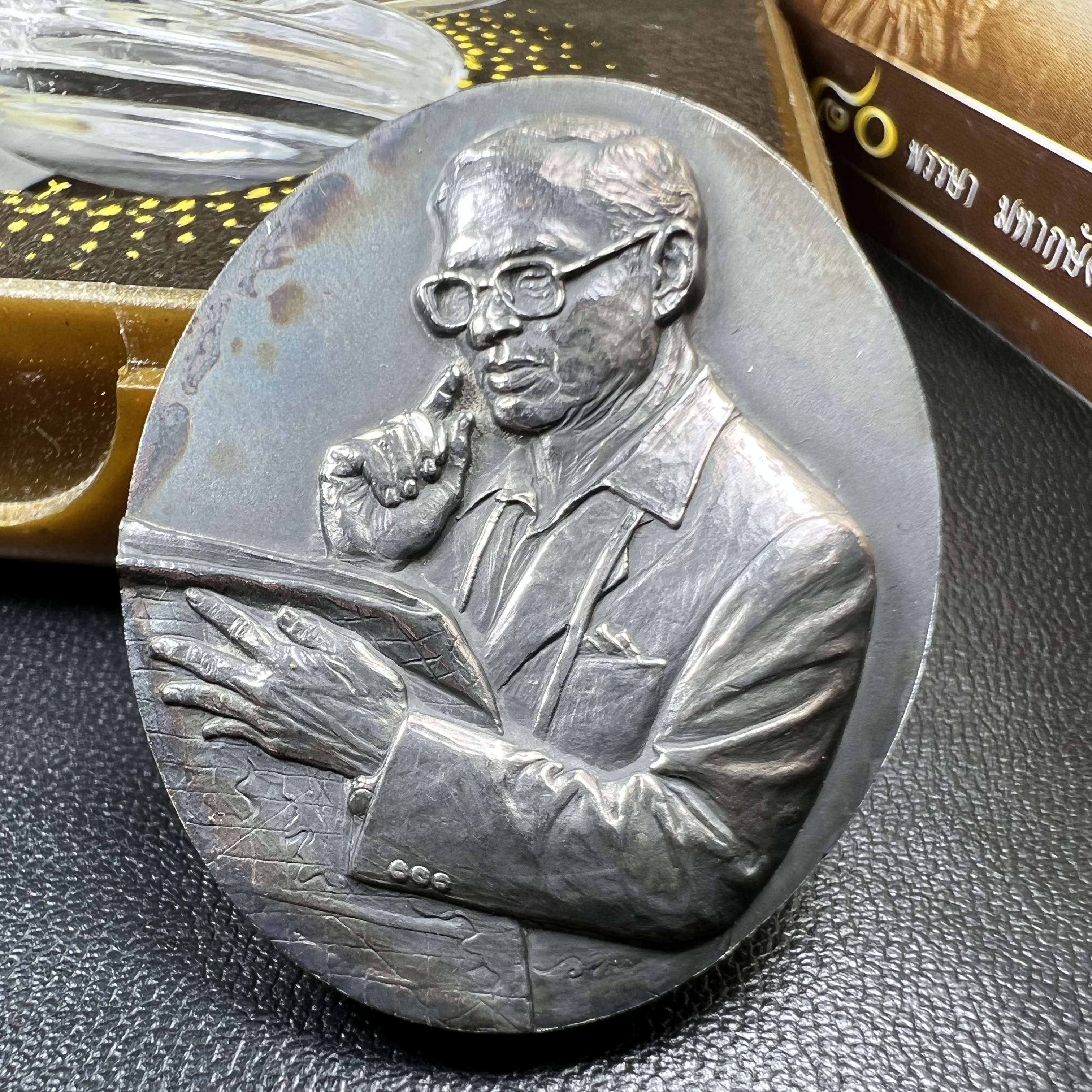 เหรียญรูปหล่อพระบาทสมเด็จพระเจ้าอยู่หัว ในหลวงทรงงาน “รุ่นเย็นศิระเพราะพระบริบาล 80พรรษา มหากษัตริย์คู่แผ่นดินสยาม” พ.ศ.2550 เนื้อเงินรมดำ(ขนาด 27*35 มม.) พร้อมกล่องบรรจุเดิมครบ