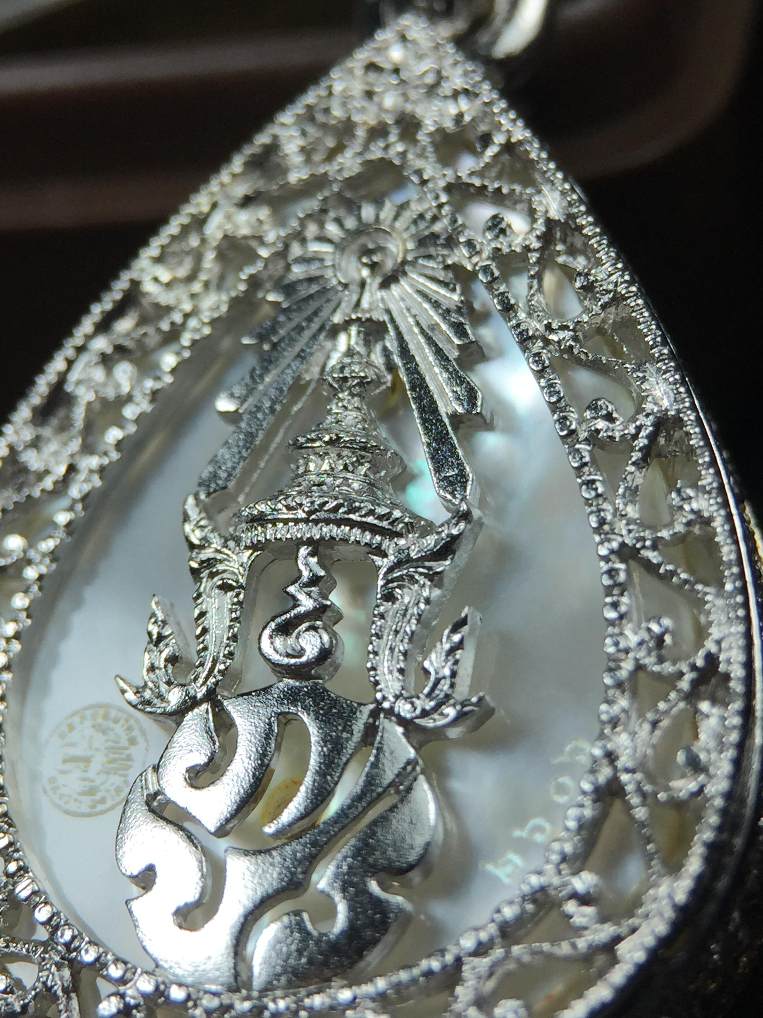 พระพุทธชินราช ภปร. โครงการ "เพราะแผ่นดินนี้ คือ แผ่นดินเกิด" ปี2548(รุ่นแรก) เหรียญทรงหยดน้ำ ขนาด 21 x 31 มม. เนื้อเงินสามกษัตริย์ องค์พระชุบสามกษัตริย์ ล้อมด้วยกรอบเงินชุบทองคำขาวสลักเสลาเป็นลวดลายละเอียดอ่อน ส่วนพื้นองค์พระเป็นเปลือกหอยมุข