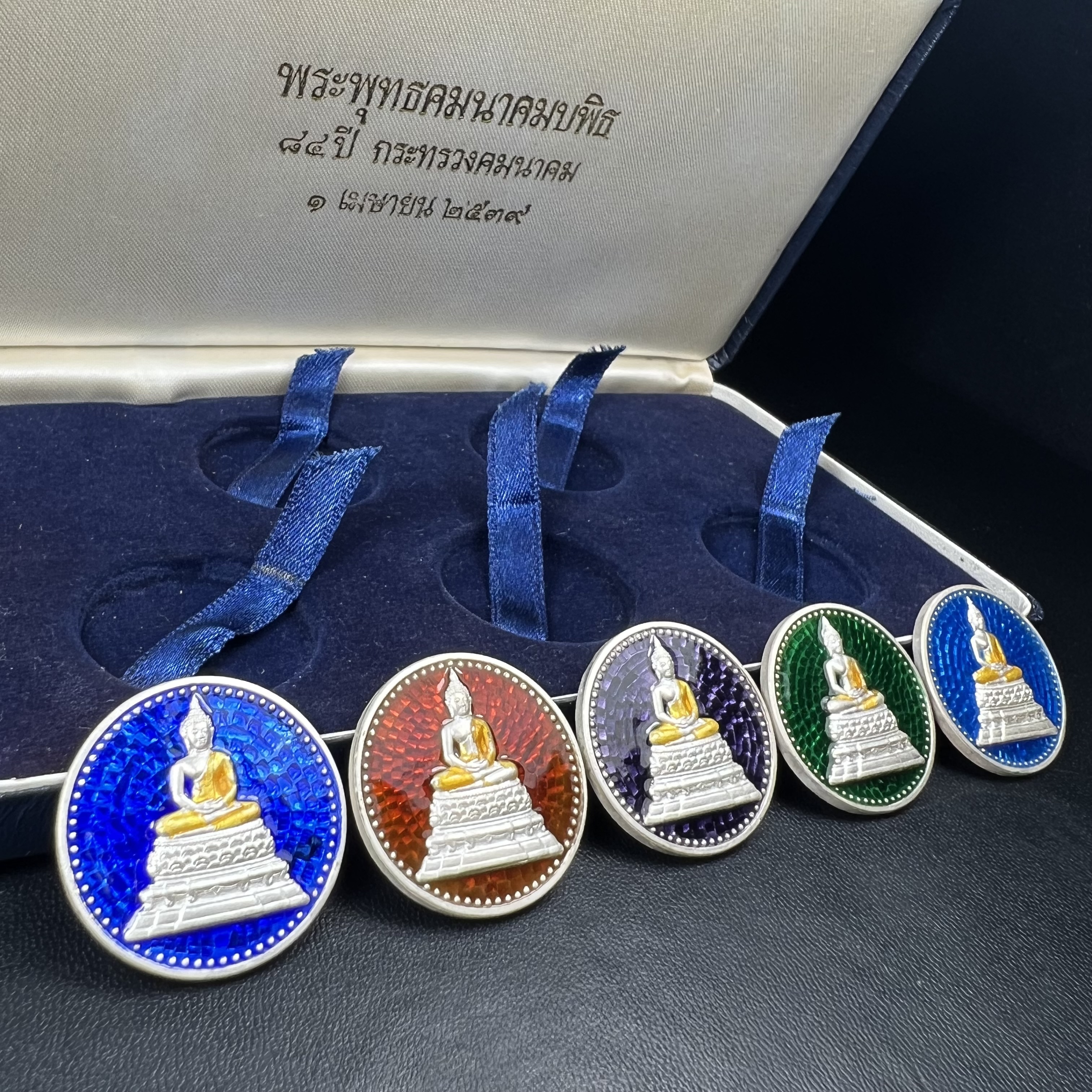 พระพุทธคมนาคมบพิธ (พระพุทธสิหิงค์จำลอง)(พระพุทธรูปประจำกระทรวงคมนาคม) หลังตรา ภปร. ครบรอบ 84 ปี กระทรวงคมนาคม พ.ศ.2539 ชุดเหรียญเนื้อเงินลงยา ขนาด 2.8 ซม. ครบชุดห้าสีพร้อมกล่องบรรจุเดิม ปลุกเสก ณ วัดพระแก้ว พิธีใหญ่