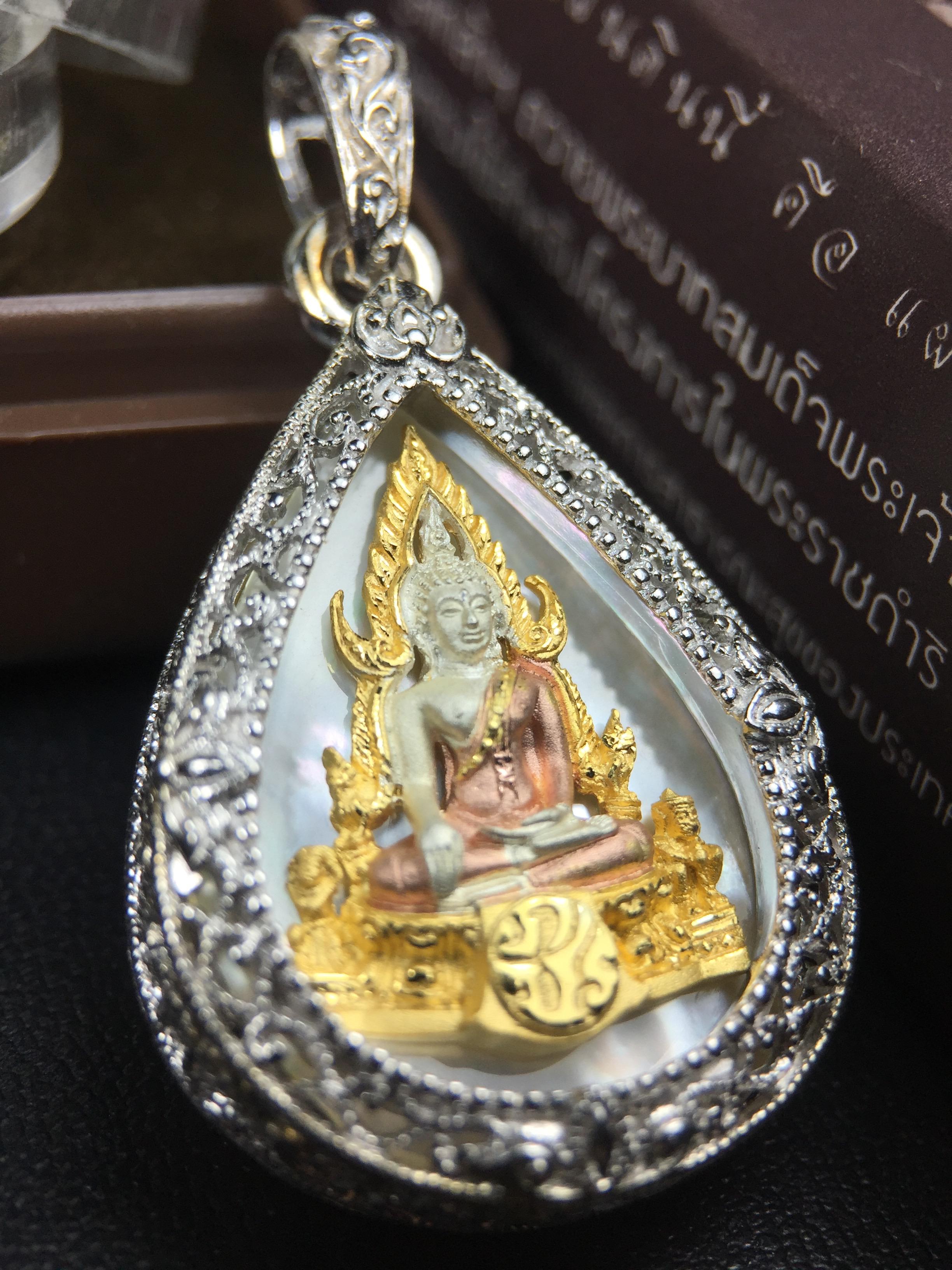 พระพุทธชินราช ภปร. โครงการ "เพราะแผ่นดินนี้ คือ แผ่นดินเกิด" ปี2548(รุ่นแรก) เหรียญทรงหยดน้ำ ขนาด 21 x 31 มม. เนื้อเงินสามกษัตริย์ องค์พระชุบสามกษัตริย์ ล้อมด้วยกรอบเงินชุบทองคำขาวสลักเสลาเป็นลวดลายละเอียดอ่อน ส่วนพื้นองค์พระเป็นเปลือกหอยมุข