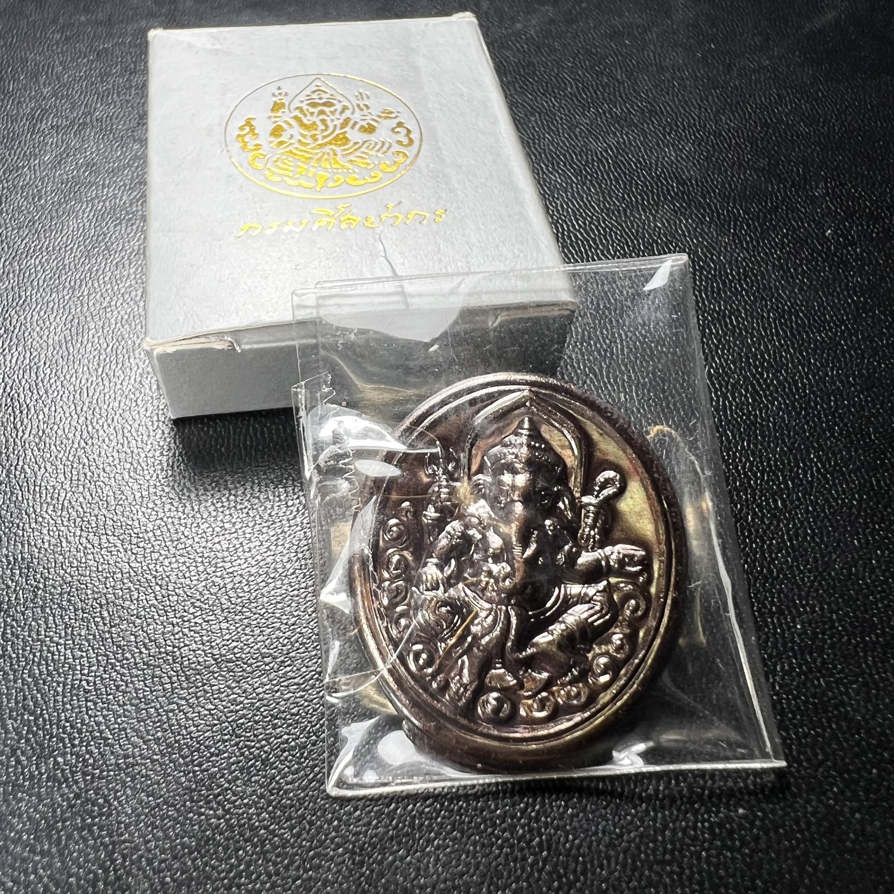 พระพิฆเนศ เทพเจ้าแห่งความสำเร็จและศิลปวิทยาการ กรมศิลปากร ปี 2547 เหรียญทองแดงรมดำ ขนาดสูง 3 ซ.ม. สภาพผิวสวยเดิม พร้อมกล่องบรรจุเดิมครบ