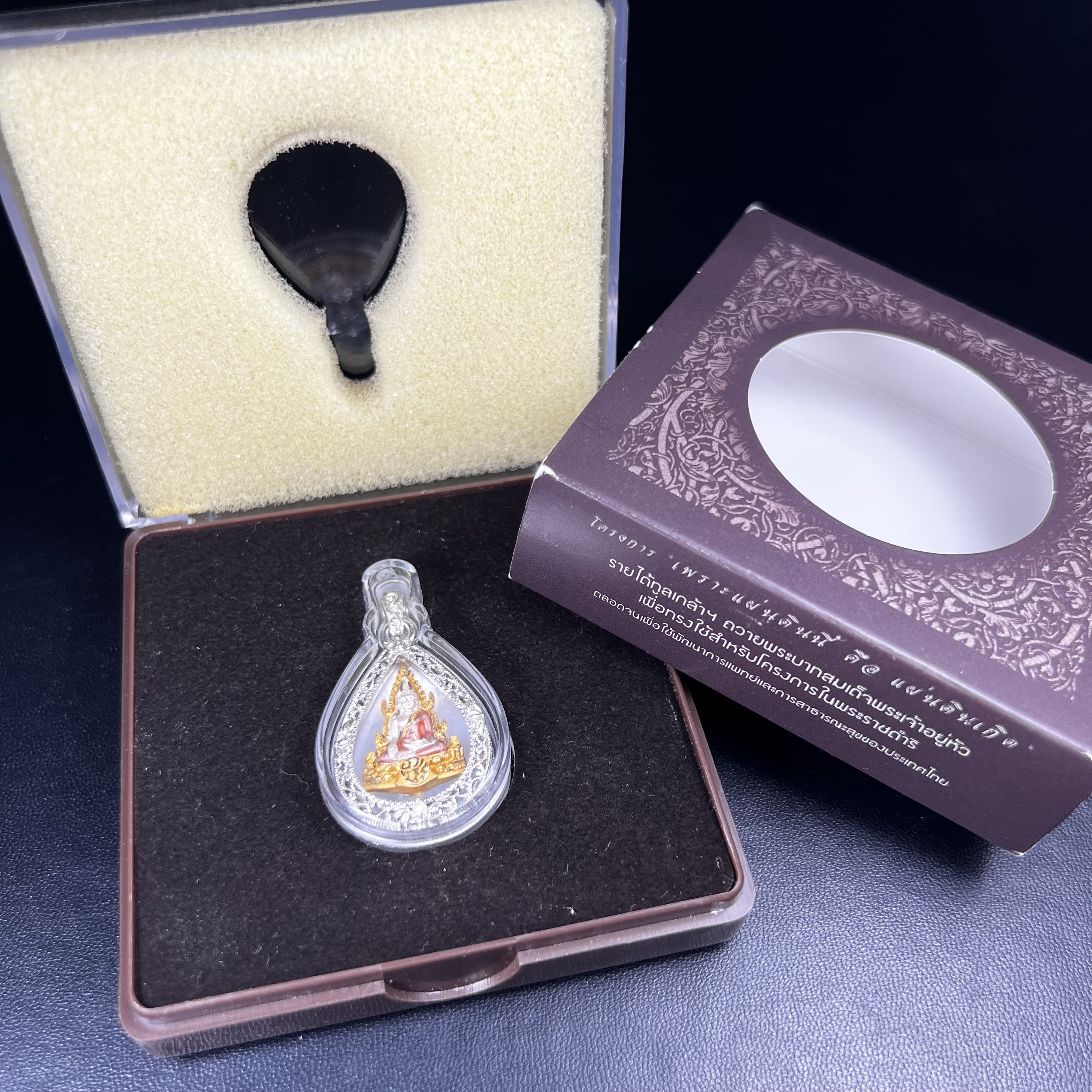 พระพุทธชินราช ภปร. โครงการ "เพราะแผ่นดินนี้ คือ แผ่นดินเกิด" ปี 2548(รุ่นแรก) เหรียญทรงหยดน้ำ ขนาด 21 x 31 มม. เนื้อเงินสามกษัตริย์ องค์พระชุบสามกษัตริย์ ล้อมด้วยกรอบเงินชุบทองคำขาวสลักเสลาเป็นลวดลายละเอียดอ่อน ส่วนพื้นองค์พระเป็นเปลือกหอยมุข