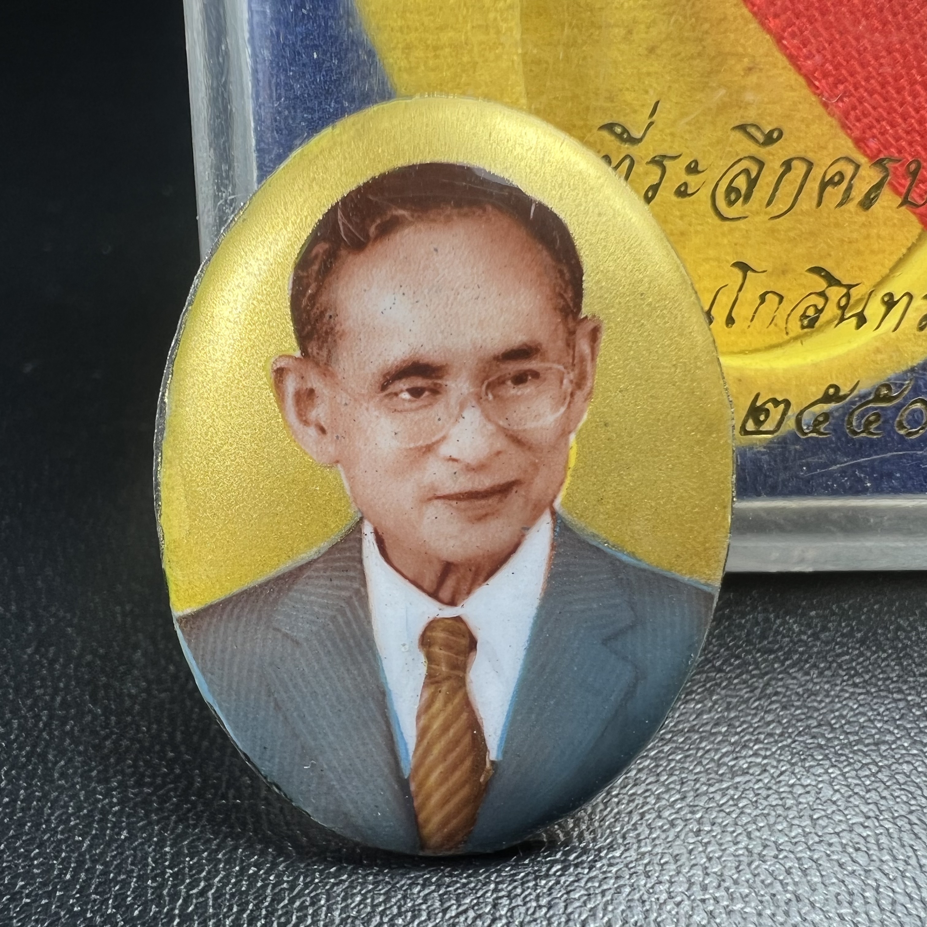 ล็อกเกตในหลวงรัชกาลที่9 ที่ระลึกครบ 25 ปี มูลนิธิศรีรัตนโกสินทร์ วัดสุทธาราม พ.ศ. 2550 พิมพ์ทรงวงรีรูปไข่เล็กฉากสีทอง หลังปิดแผ่นโลหะสีขาว(สแตนเลส)ฝังพระยอดธง(นิยม)