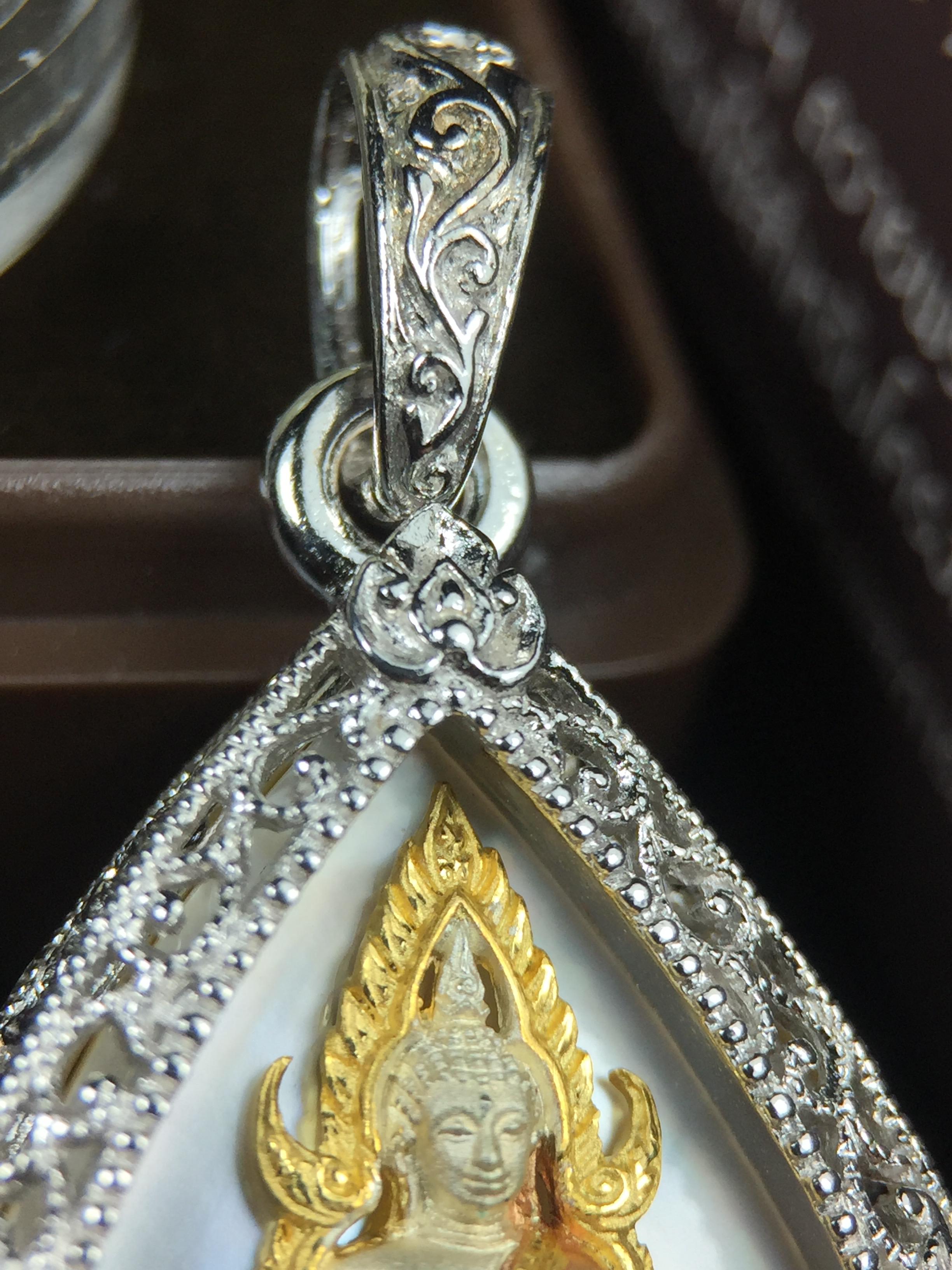 พระพุทธชินราช ภปร. โครงการ "เพราะแผ่นดินนี้ คือ แผ่นดินเกิด" ปี2548(รุ่นแรก) เหรียญทรงหยดน้ำ ขนาด 21 x 31 มม. เนื้อเงินสามกษัตริย์ องค์พระชุบสามกษัตริย์ ล้อมด้วยกรอบเงินชุบทองคำขาวสลักเสลาเป็นลวดลายละเอียดอ่อน ส่วนพื้นองค์พระเป็นเปลือกหอยมุข