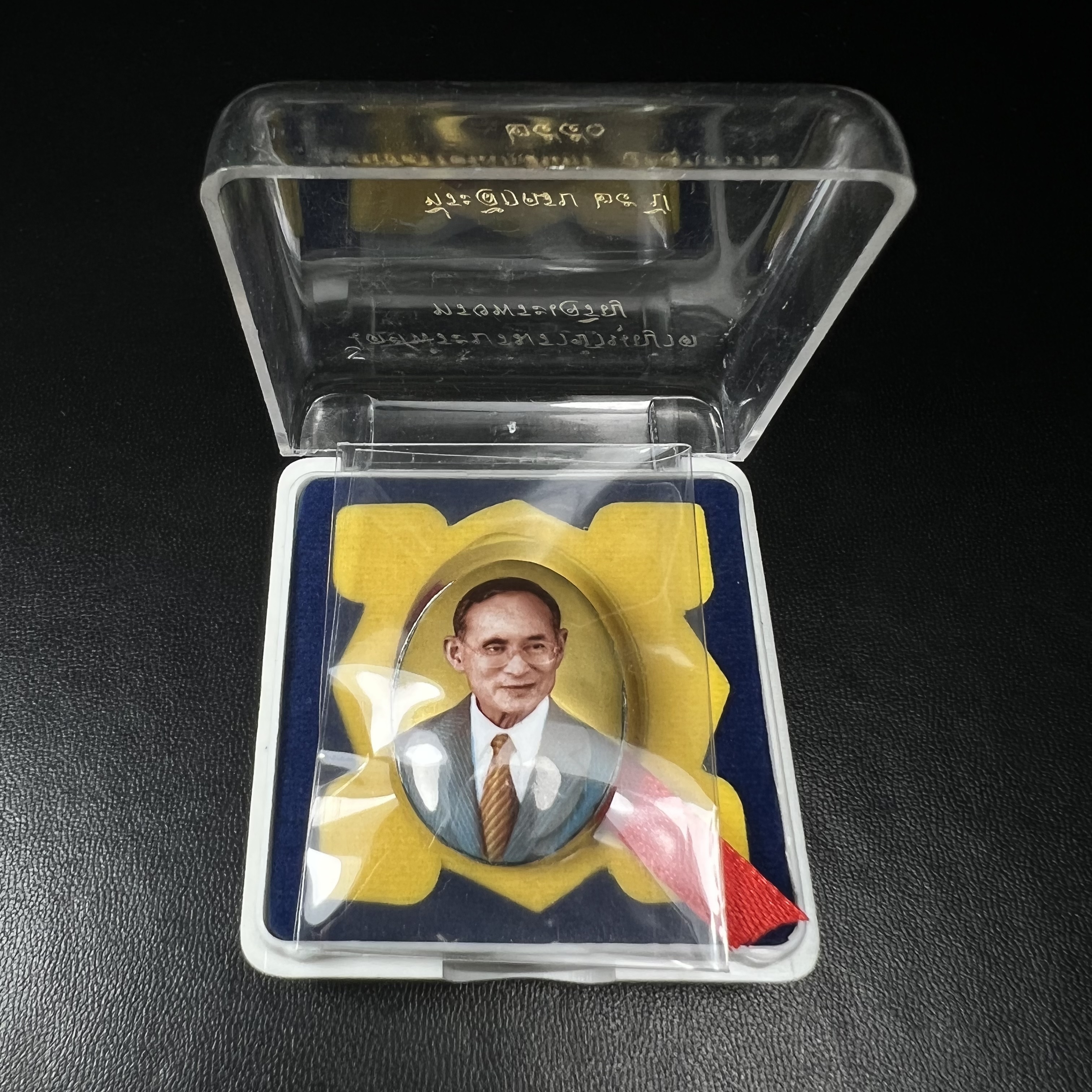 ล็อกเกตในหลวงรัชกาลที่9 ที่ระลึกครบ 25 ปี มูลนิธิศรีรัตนโกสินทร์ วัดสุทธาราม พ.ศ. 2550 พิมพ์ทรงวงรีรูปไข่เล็กฉากสีทอง หลังปิดแผ่นโลหะสีขาว(สแตนเลส)ฝังพระยอดธง(นิยม)