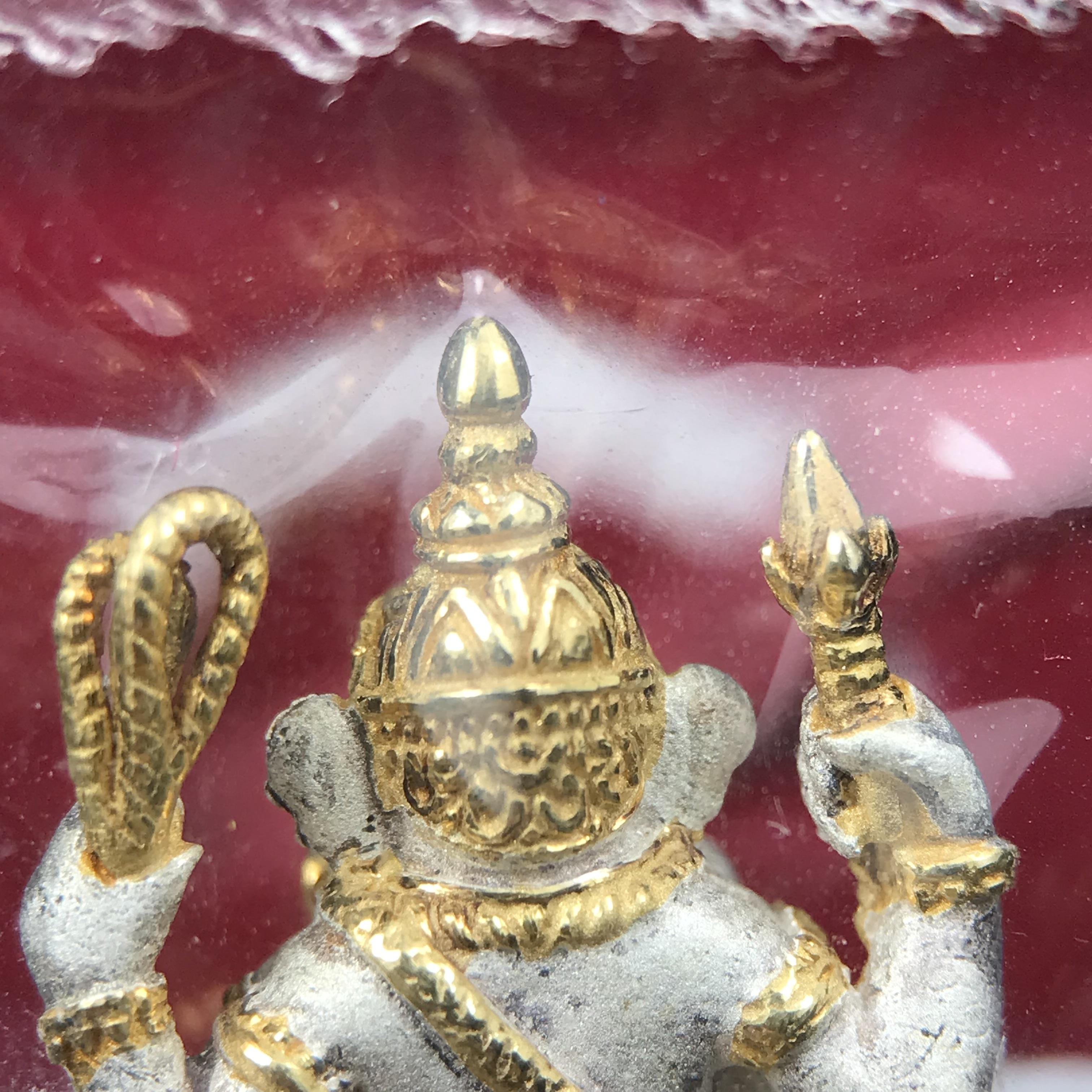 พระพิฆเนศวร รุ่น คชสารหมื่นปี รูปเหมือนพระพิฆเนศวรนั่งประทานพรฐานงาช้างแมมมอสขนาดห้อยคอ เนื้อเงินชุบสามกษัตริย์ขัดเงา พิมพ์เล็ก สูง 2.2 ซม. ฝังพลอยทับทิมแท้ พิธีมหาเทวาภิเษก ณ. เทวสถานโบสถ์พราหมณ์ (เสาชิงช้า) โดยเกจิคณาจารย์ทั่วประทศ ปี 2545(หมายเลข ๓๐)