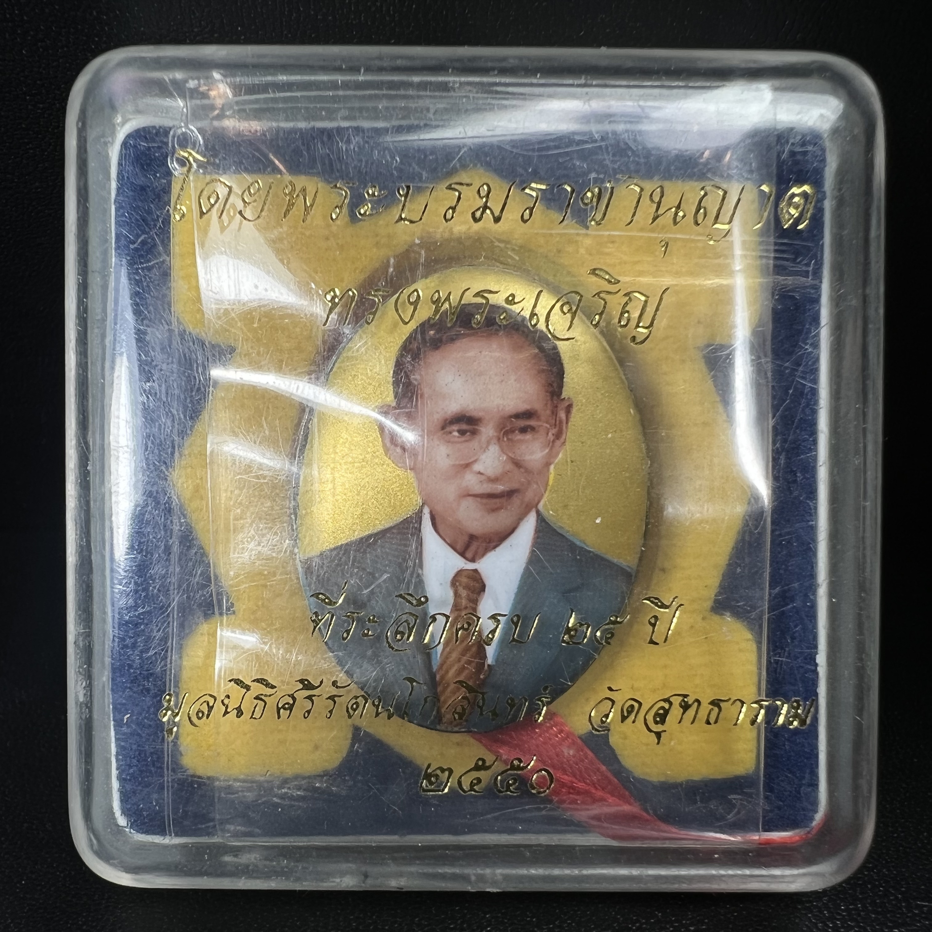 ล็อกเกตในหลวงรัชกาลที่9 ที่ระลึกครบ 25 ปี มูลนิธิศรีรัตนโกสินทร์ วัดสุทธาราม พ.ศ. 2550 พิมพ์ทรงวงรีรูปไข่เล็กฉากสีทอง หลังปิดแผ่นโลหะสีขาว(สแตนเลส)ฝังพระยอดธง(นิยม)