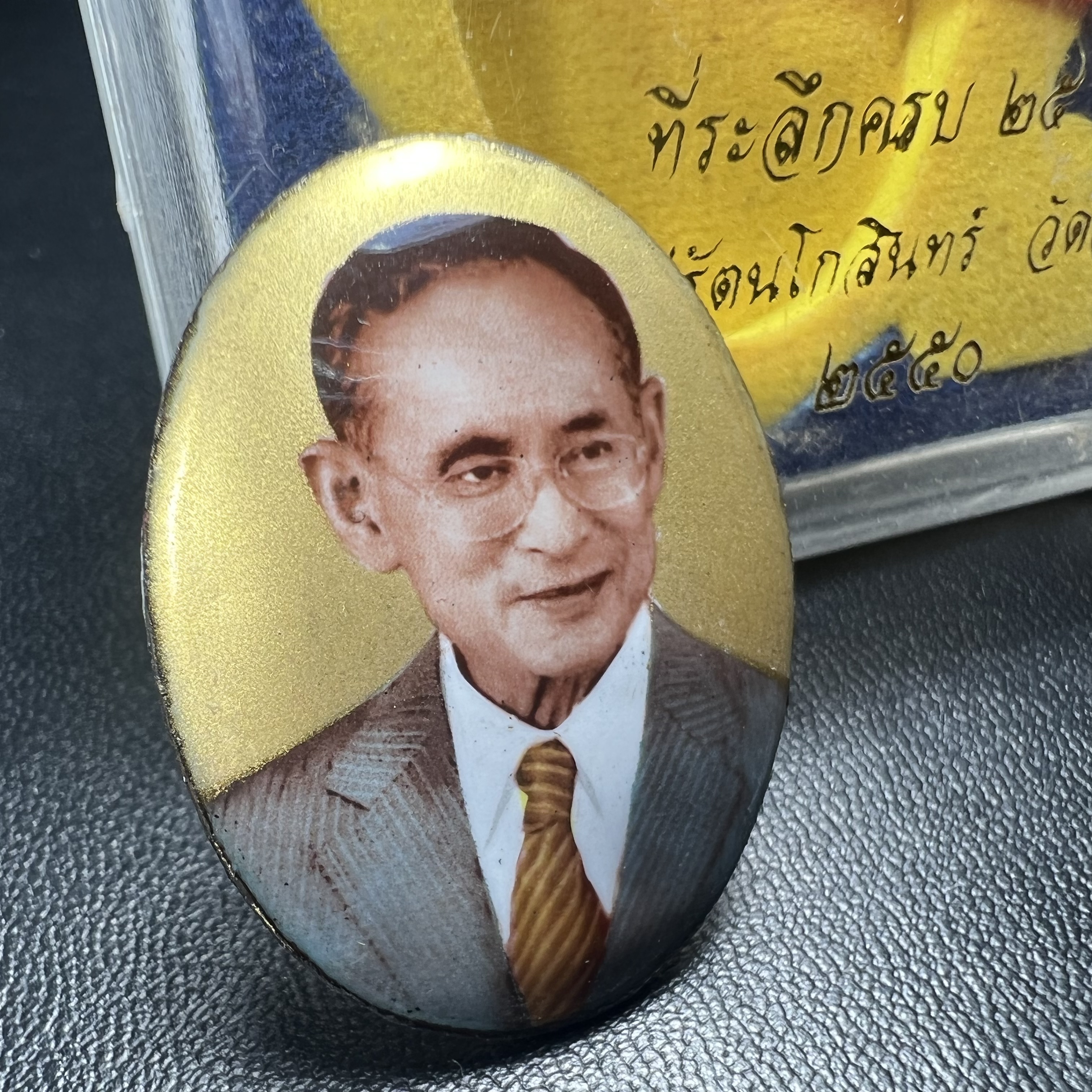 ล็อกเกตในหลวงรัชกาลที่9 ที่ระลึกครบ 25 ปี มูลนิธิศรีรัตนโกสินทร์ วัดสุทธาราม พ.ศ. 2550 พิมพ์ทรงวงรีรูปไข่เล็กฉากสีทอง หลังปิดแผ่นโลหะสีขาว(สแตนเลส)ฝังพระยอดธง(นิยม)