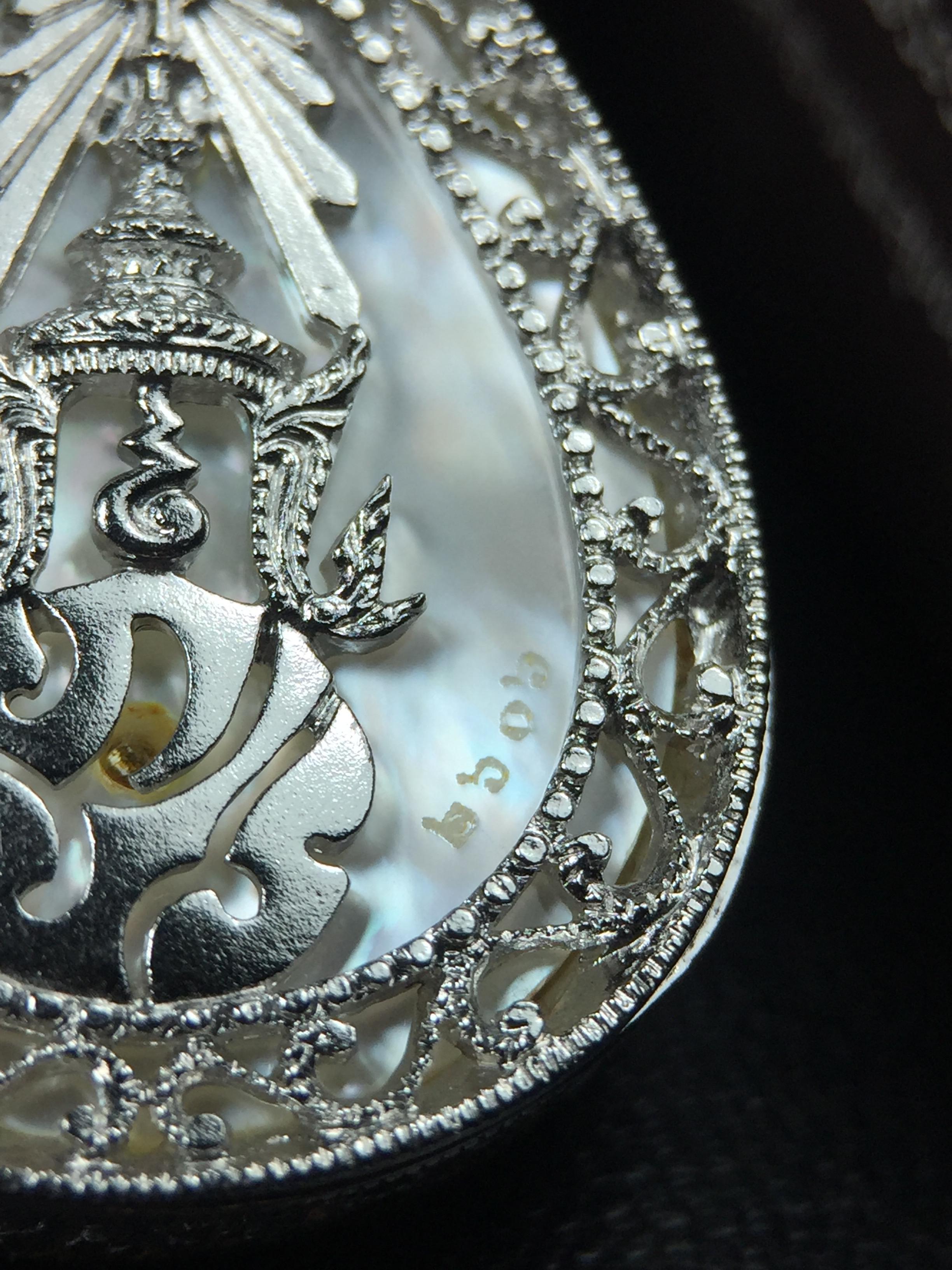 พระพุทธชินราช ภปร. โครงการ "เพราะแผ่นดินนี้ คือ แผ่นดินเกิด" ปี2548(รุ่นแรก) เหรียญทรงหยดน้ำ ขนาด 21 x 31 มม. เนื้อเงินสามกษัตริย์ องค์พระชุบสามกษัตริย์ ล้อมด้วยกรอบเงินชุบทองคำขาวสลักเสลาเป็นลวดลายละเอียดอ่อน ส่วนพื้นองค์พระเป็นเปลือกหอยมุข