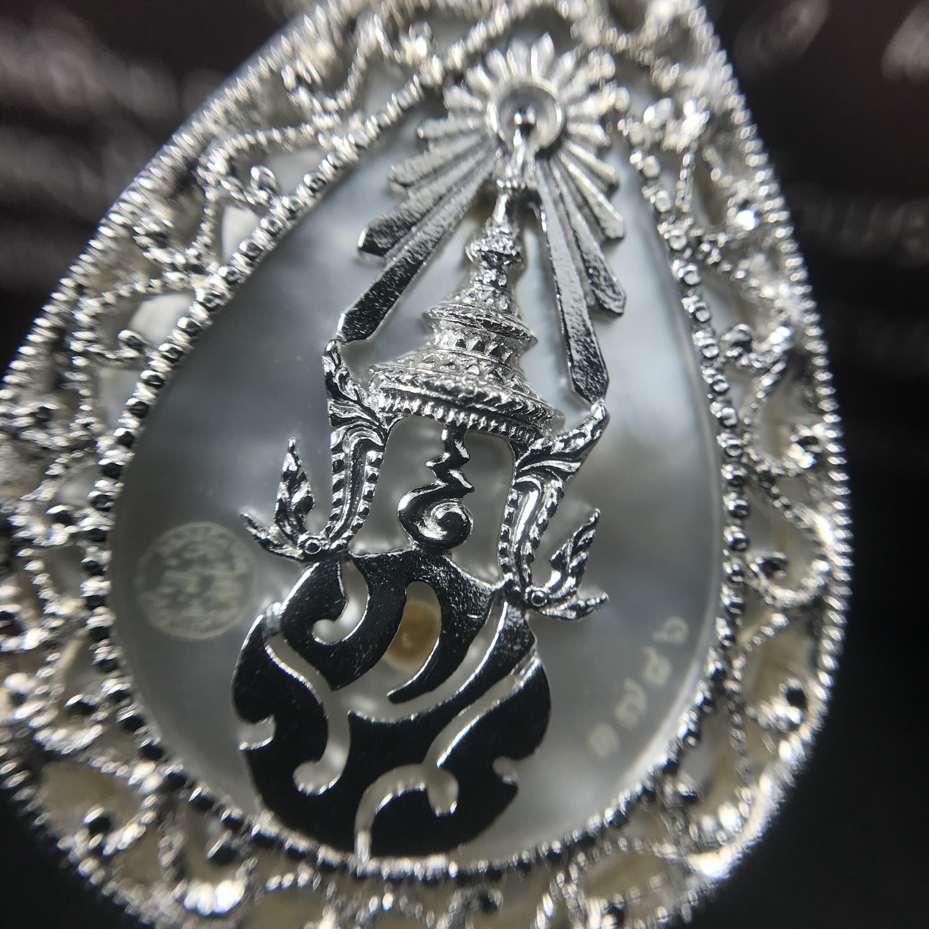 พระพุทธชินราช ภปร. โครงการ "เพราะแผ่นดินนี้ คือ แผ่นดินเกิด" ปี2548(รุ่นแรก) เหรียญทรงหยดน้ำ ขนาด 21 x 31 มม. เนื้อเงินสามกษัตริย์ องค์พระชุบสามกษัตริย์ ล้อมด้วยกรอบเงินชุบทองคำขาวสลักเสลาเป็นลวดลายละเอียดอ่อน ส่วนพื้นองค์พระเป็นเปลือกหอยมุข