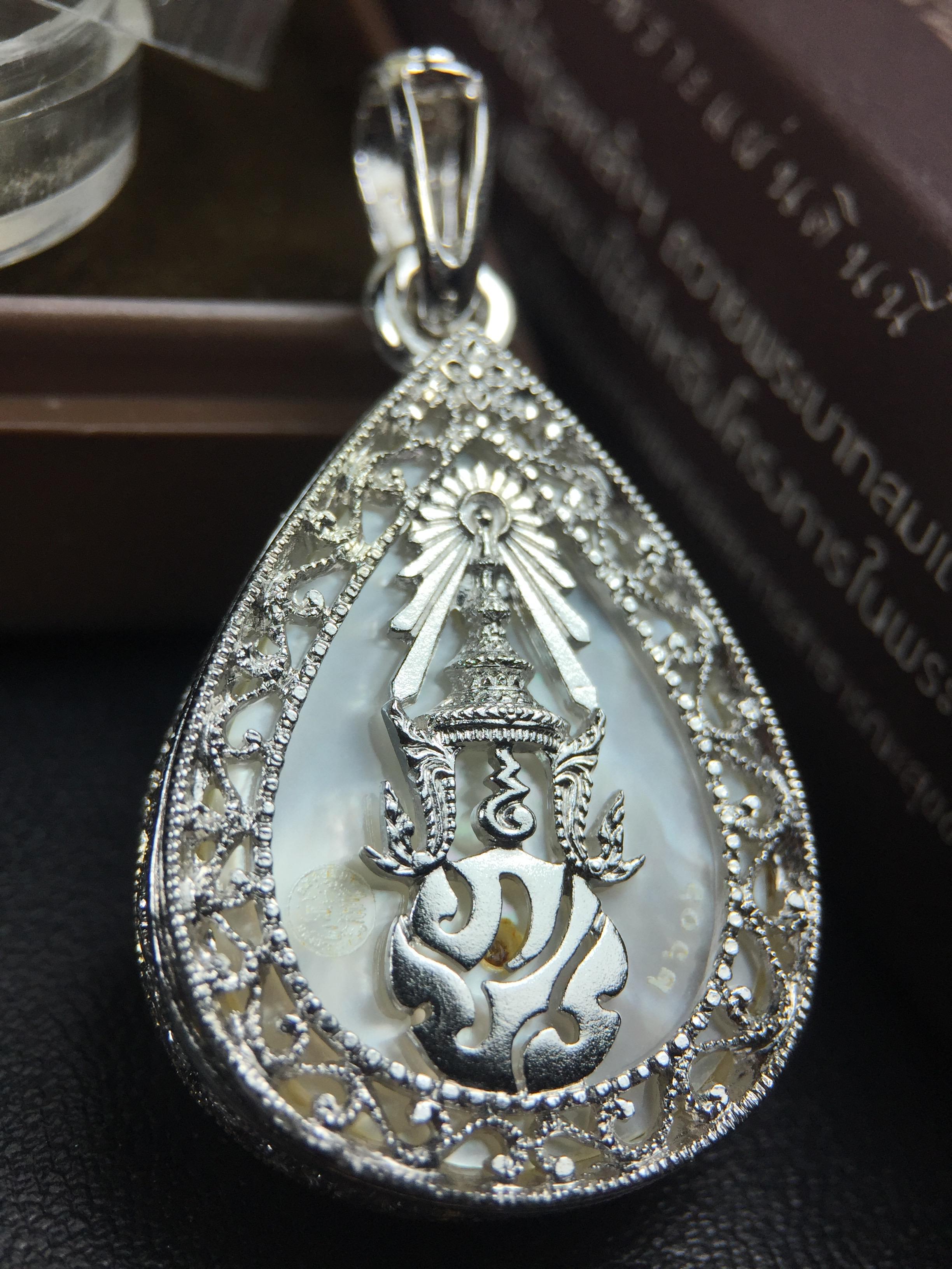 พระพุทธชินราช ภปร. โครงการ "เพราะแผ่นดินนี้ คือ แผ่นดินเกิด" ปี2548(รุ่นแรก) เหรียญทรงหยดน้ำ ขนาด 21 x 31 มม. เนื้อเงินสามกษัตริย์ องค์พระชุบสามกษัตริย์ ล้อมด้วยกรอบเงินชุบทองคำขาวสลักเสลาเป็นลวดลายละเอียดอ่อน ส่วนพื้นองค์พระเป็นเปลือกหอยมุข