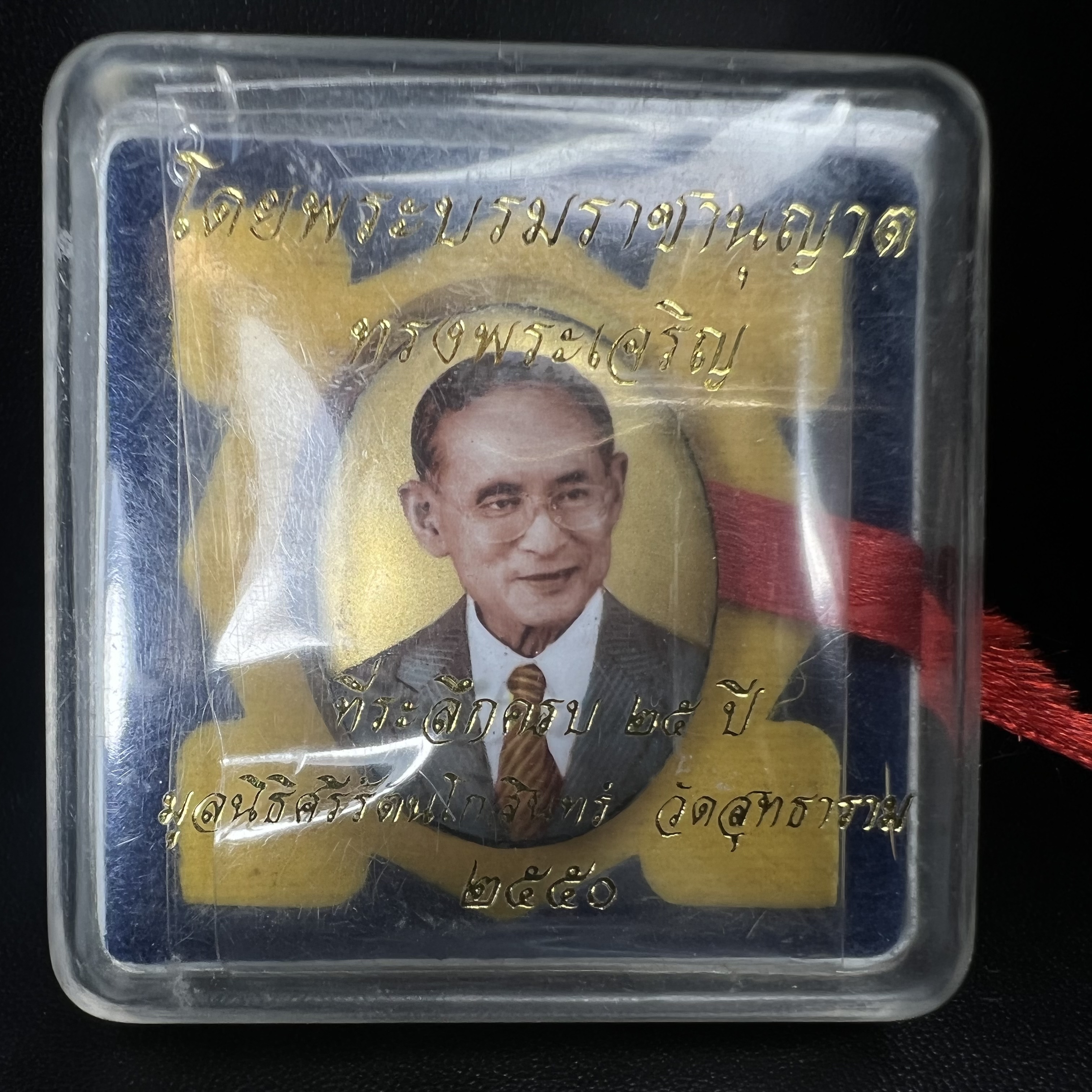 ล็อกเกตในหลวงรัชกาลที่9 ที่ระลึกครบ 25 ปี มูลนิธิศรีรัตนโกสินทร์ วัดสุทธาราม พ.ศ. 2550 พิมพ์ทรงวงรีรูปไข่เล็กฉากสีทอง หลังปิดแผ่นโลหะสีขาว(สแตนเลส)ฝังพระยอดธง(นิยม)